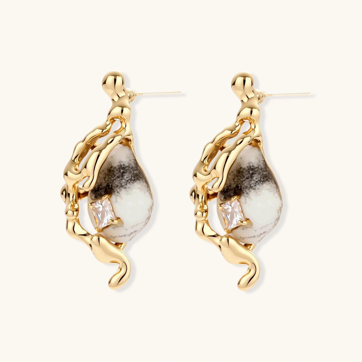 Close-up of metallic dragon-wrapped earrings with marbled resin stones on white background