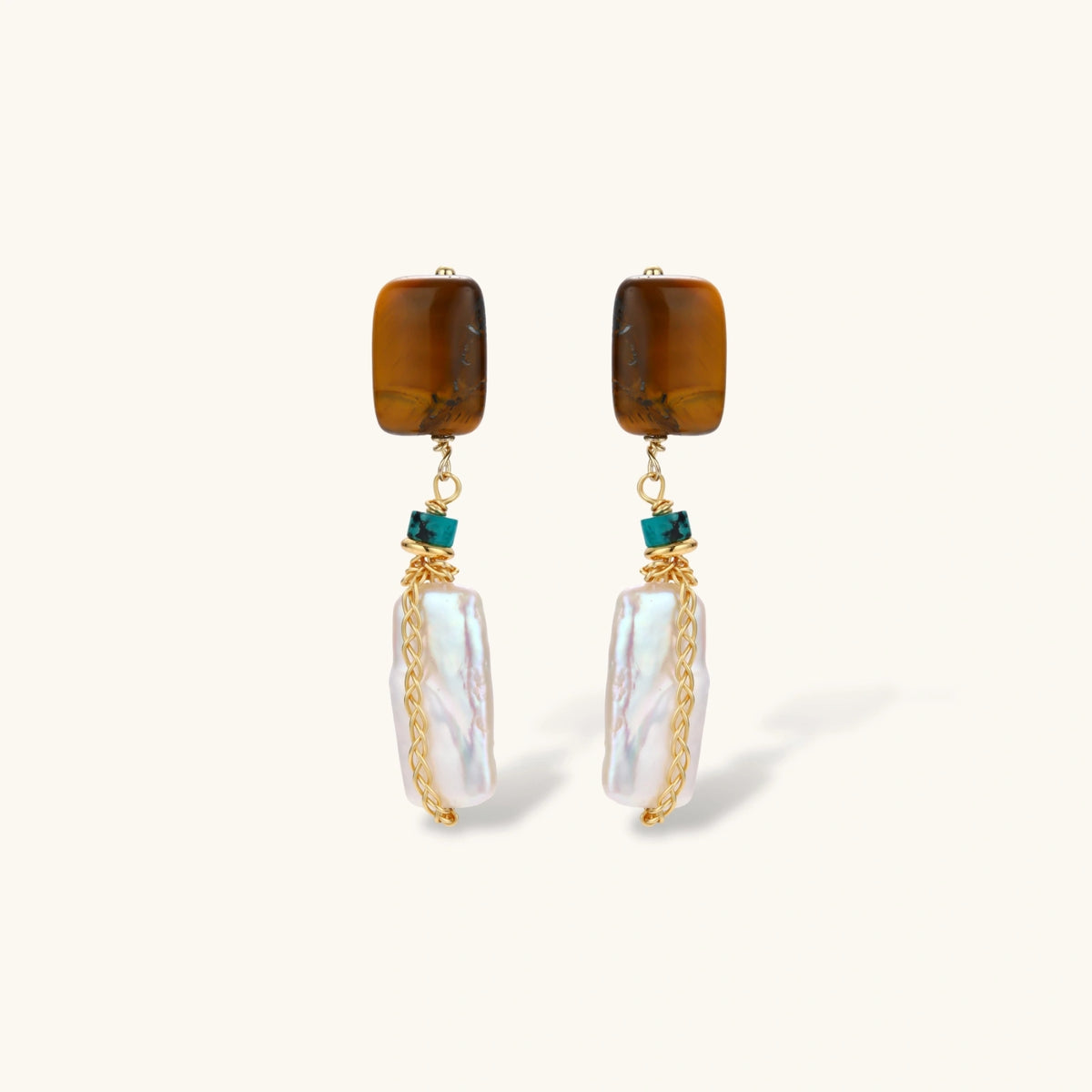 Gold-plated drop earrings with amber stones, teal beads, and wire-wrapped baroque pearls on cream background.