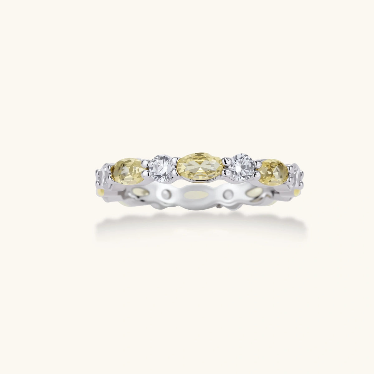 Platinum-plated copper ring with alternating clear and pale yellow oval stones in an eternity band design on white background.